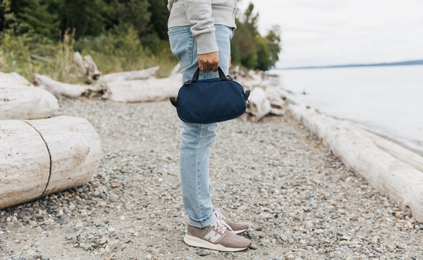 a person at the beach holding a Navy Parapack Grab Bag.